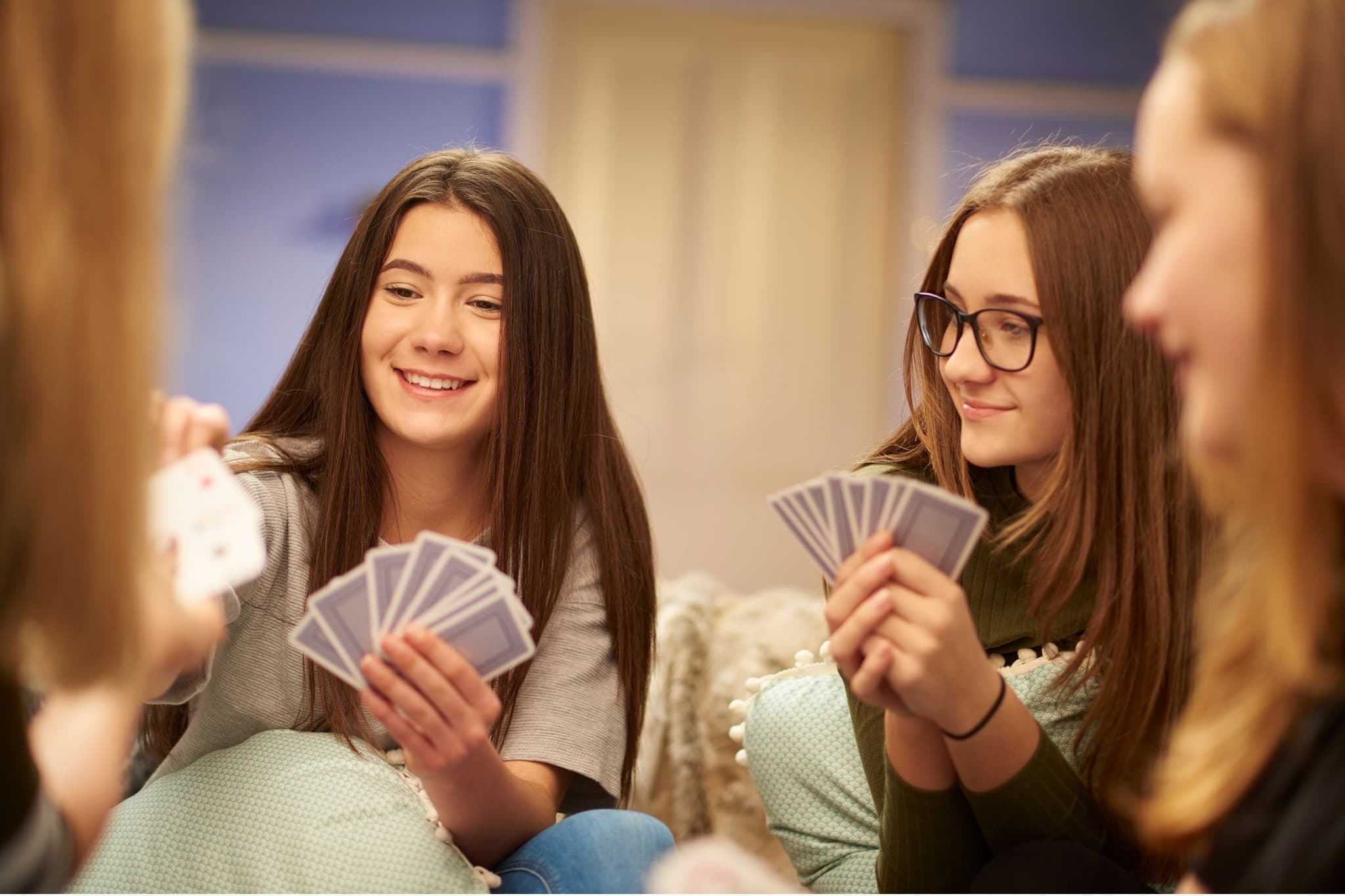 Four people holding playing cards during a game.