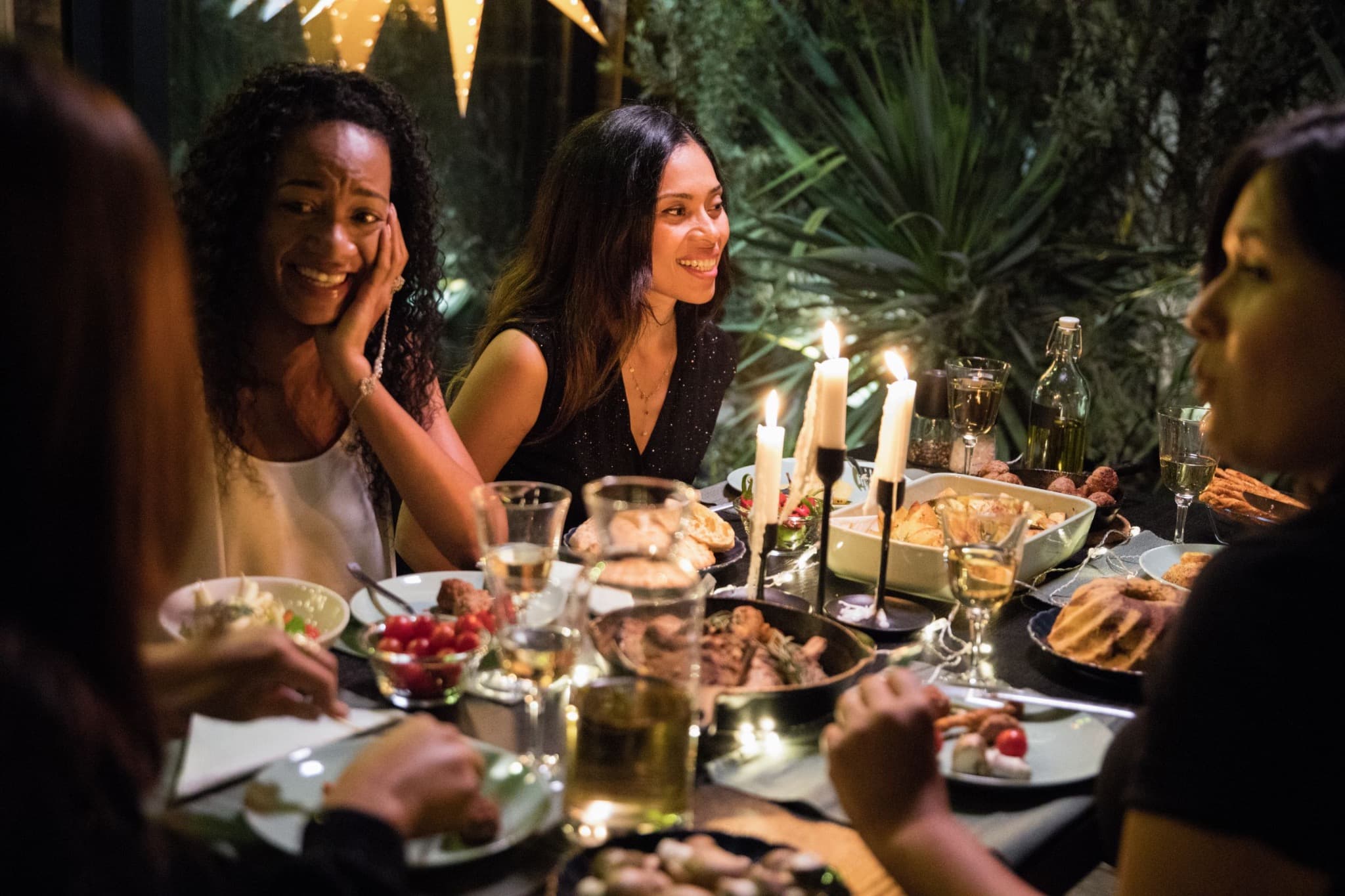 Friends sharing a candlelit meal around a table.