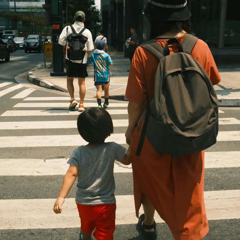 A parent holding a small child’s hand while crossing the street